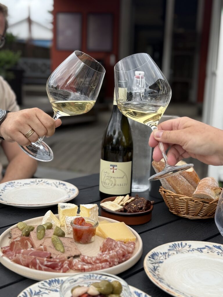 To personer skåler med hvidvin over en tapasplatte på udendørs vinbar.